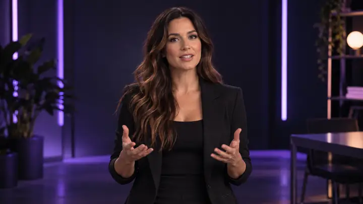 Filmisches, weitwinkliges Studioporträt eines Marketingprofis, der zur Kamera spricht, mittig vor einem dunklen Hintergrund mit weichem violettem Licht und dezenten vertikalen Lichtleisten